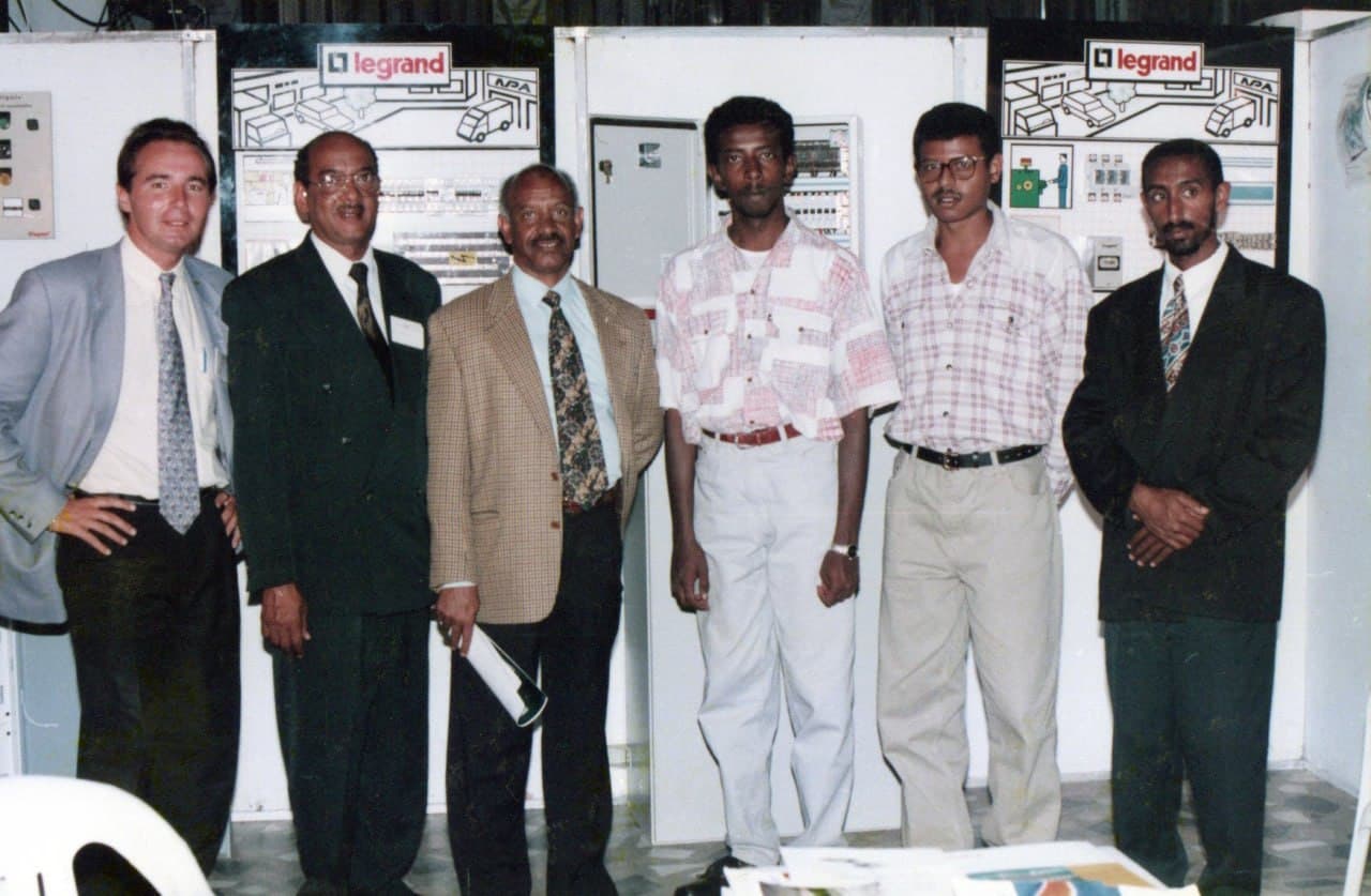 The Dama team at a trade stand, switchgear panels behind them
