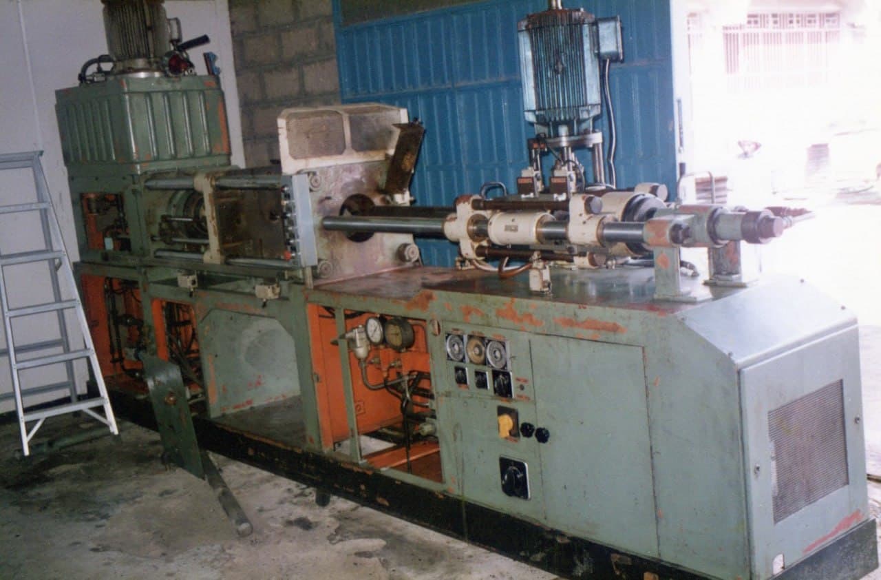 A long machine on the workshop floor, shaft and motor mounted along the top, blue shutter behind